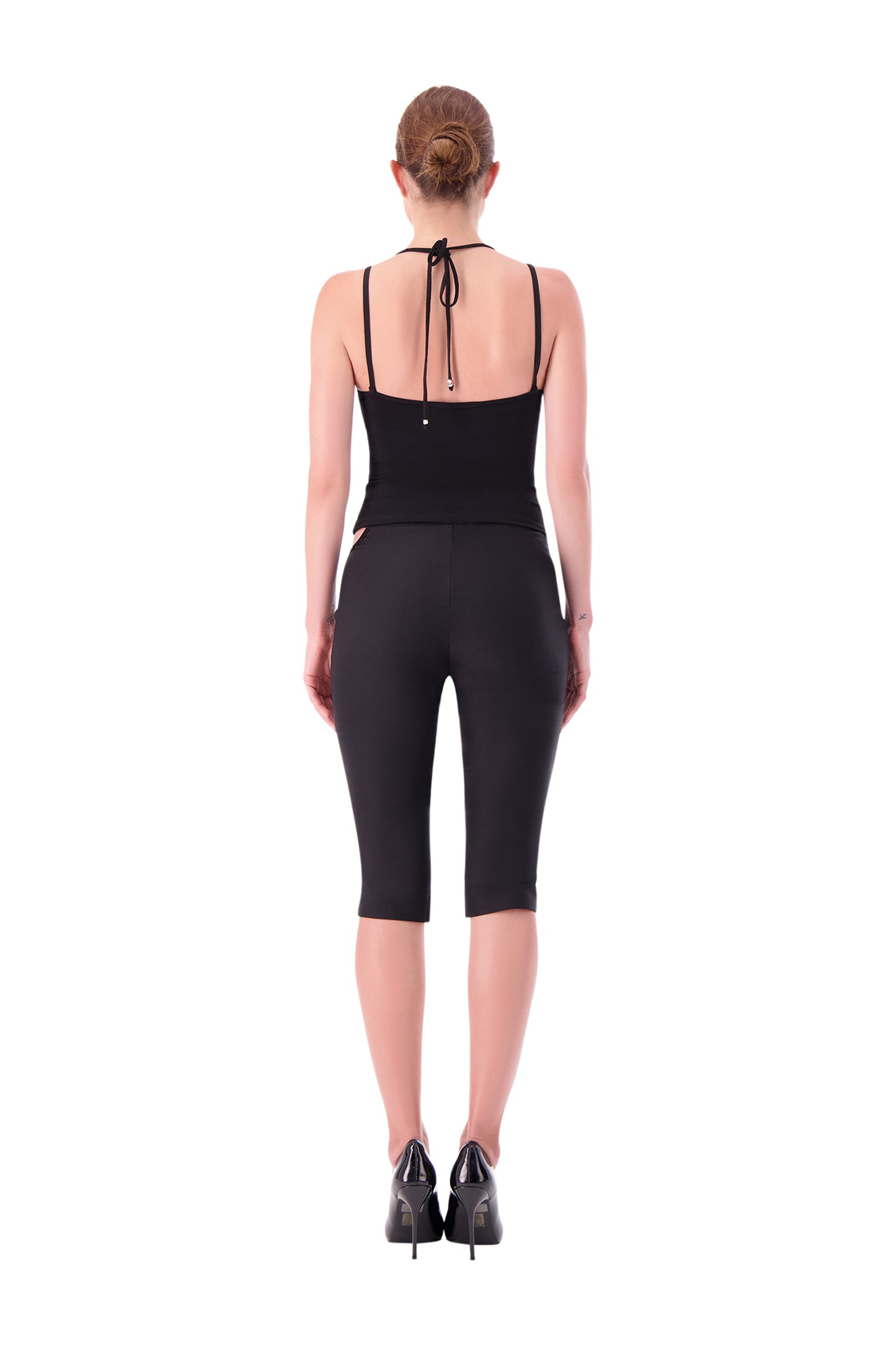 Woman wearing a black outfit with a tie-back top on a white background