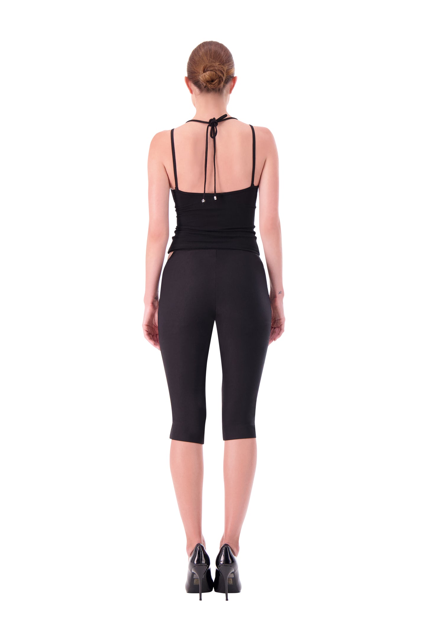 Person wearing a black outfit with a unique back design on a white background