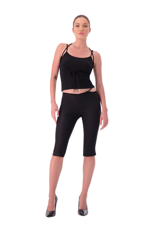 Woman wearing a black sleeveless top and black capri leggings on a white background